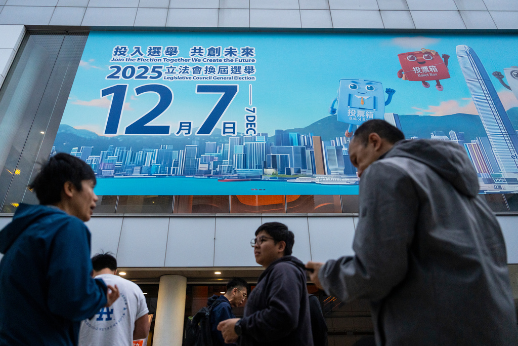 Pedestrians walk past the banner promoting the Hong Kong Legislative Council General Election in Hong Kong on Wednesday, Dec. 3, 2025. (AP Photo/Chan Long Hei)