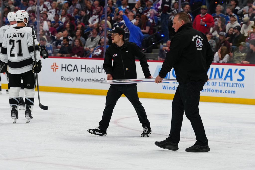 Members of the Colorado Avalanche conversion crew carry a new piece of glass to the Los Angeles Kings' bench during the second period of Game 2 in the first round of the NHL hockey Stanley Cup playoffs against the Colorado Avalanche, Tuesday, April 21, 2026, in Denver. (AP Photo/Jack Dempsey)