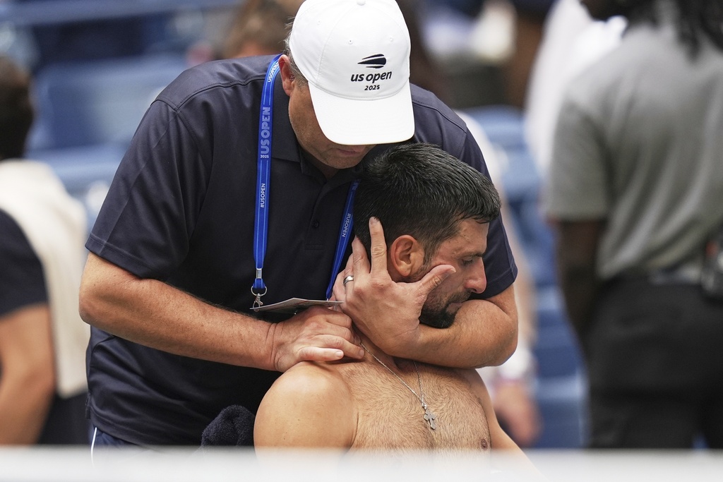 Novak Djokovic, of Serbia, has his back stretched during the men's singles semifinals of the U.S. Open tennis championships, Friday, Sept. 5, 2025, in New York. (AP Photo/Seth Wenig)