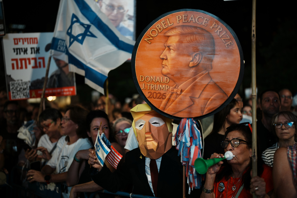 A man wearing a mask resembling U.S. President Donald Trump holds a sign designed like a Nobel Peace Prize medal during a rally in support of hostages held by Hamas, at Hostages Square in Tel Aviv, Israel, Saturday, Oct. 11, 2025, ahead of the expected release of those held in the Gaza Strip. (AP Photo/Emilio Morenatti)