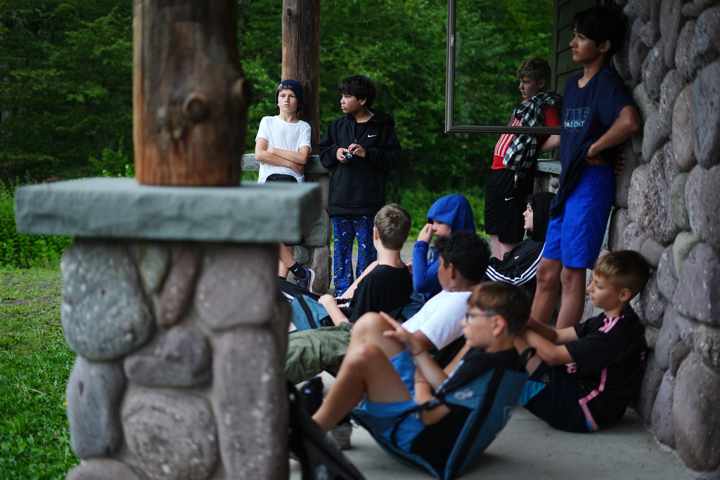 Dylan Aristy Mota, 12, of New York City, who has lupus, second from left, and fellow campers take shelter from the rain at the Frost Valley YMCA sleepaway camp in Claryville, N.Y., Thursday, July 31, 2025. The camp partnered with Children's Hospital at Montefiore so kids with autoimmune diseases could attend for the first time. (AP Photo/Matt Rourke)