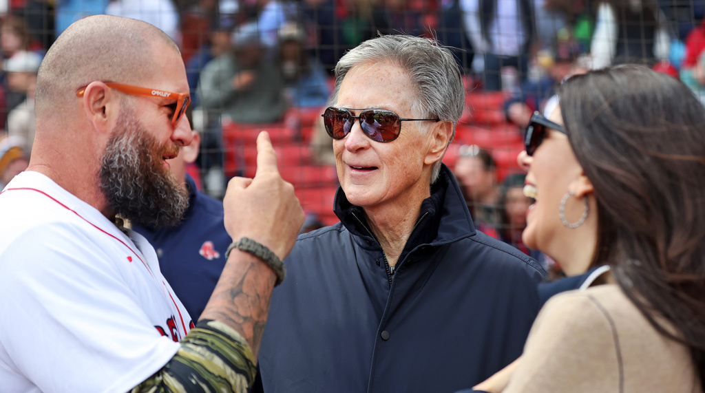 FILE - From left, former Red Sox player Jonny Gomes, team owner John Henry, and his wife Linda Pizzuti Henry, talk on the field before a Red Sox baseball game against the Detroit Tigers, April 20, 2026, in Boston. (AP Photo/Jim Davis, File)