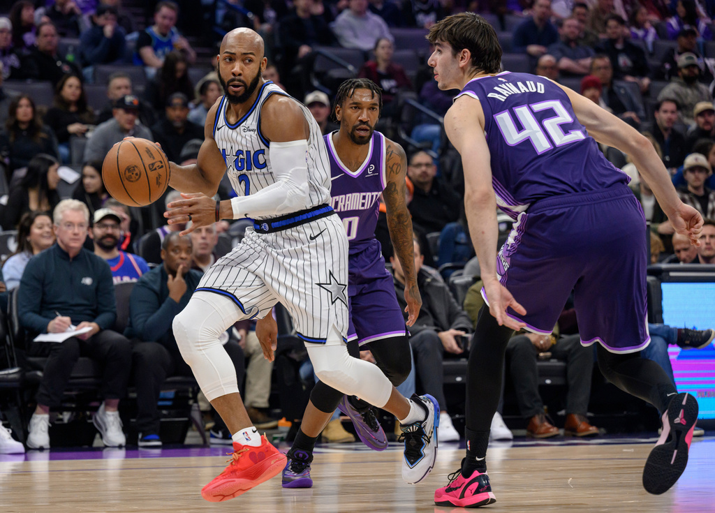 Orlando Magic guard Jevon Carter, left, dribbles past Sacramento Kings guard Malik Monk (0) and center Maxime Raynaud (42) during the first half of an NBA basketball game in Sacramento, Calif., Thursday, Feb. 19, 2026. (AP Photo/Randall Benton)