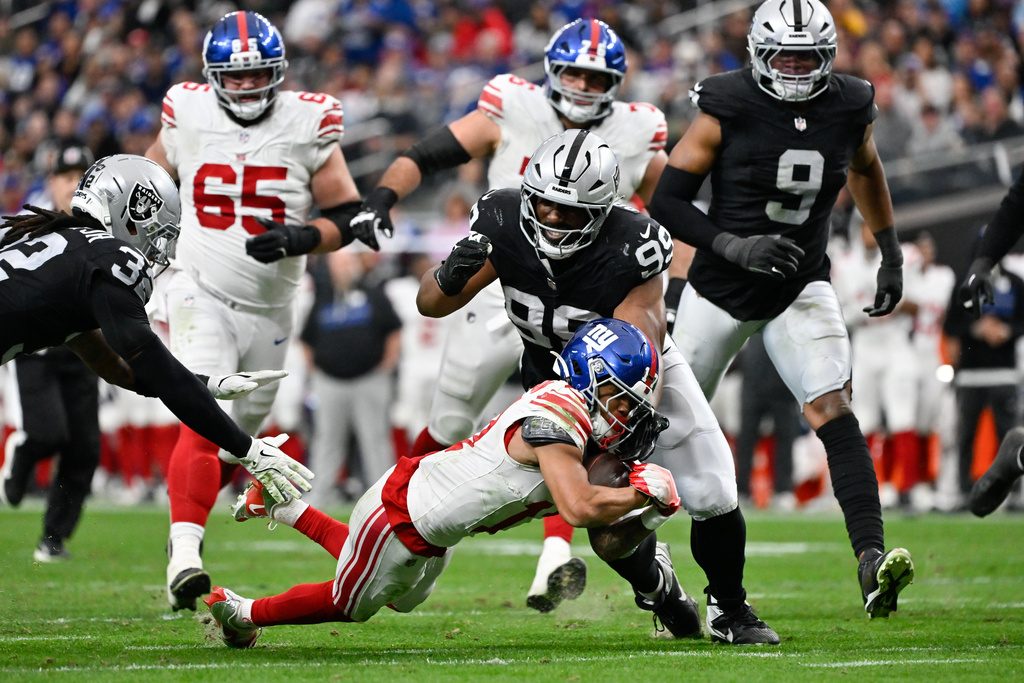 Las Vegas Raiders defensive tackle Thomas Booker IV (99) tackles New York Giants wide receiver Wan'Dale Robinson (17) during the first half of an NFL football game Sunday, Dec. 28, 2025, in Las Vegas. (AP Photo/David Becker)