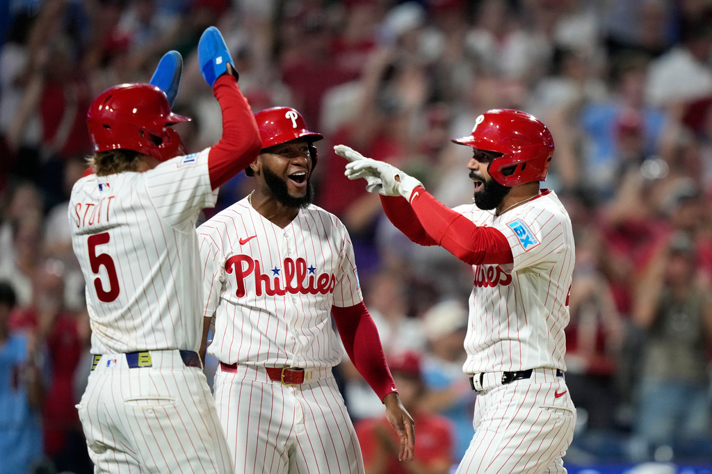 Philadelphia Phillies' Derek Hill, from right, celebrates with Bryan de la Cruz and Bryson Stott after hitting a grand slam against Washington Nationals pitcher Tom Cosgrove during the seventh inning of a baseball game Monday, Aug. 3, 2026, in Philadelphia. (AP Photo/Matt Slocum)