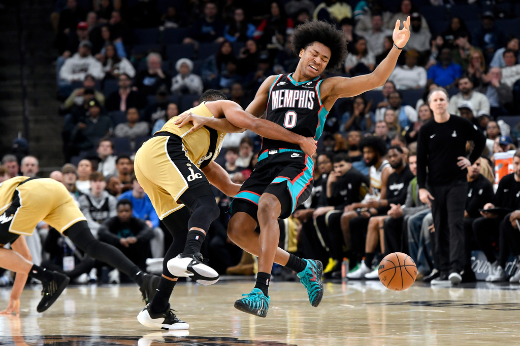 Washington Wizards guard CJ McCollum, center left, fouls Memphis Grizzlies forward Jaylen Wells (0) in the first half of an NBA basketball game Saturday, Dec. 20, 2025, in Memphis, Tenn. (AP Photo/Brandon Dill)