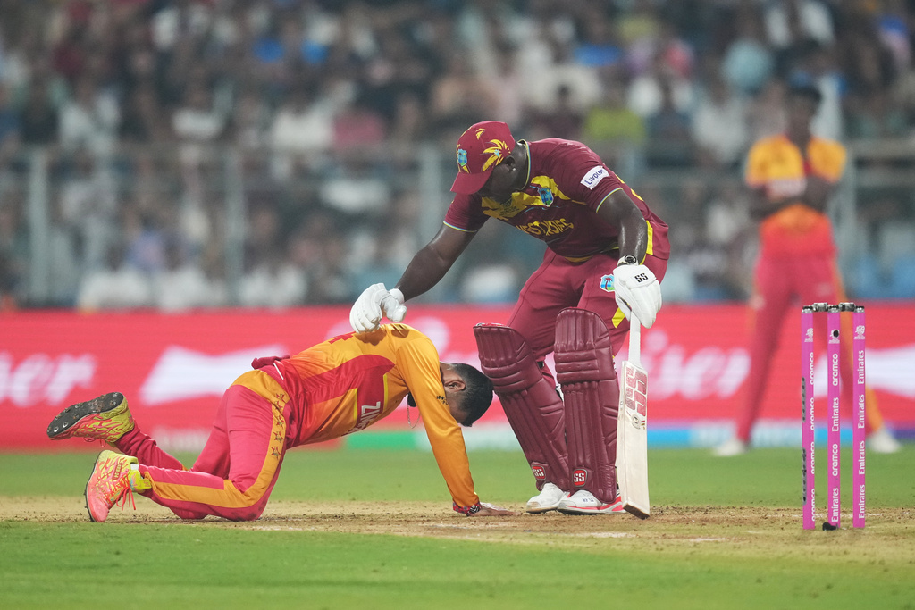 West Indies' Rovman Powell, right, comforts as Zimbabwe's captain Sikandar Raza felt on ground after he was hit by the ball during the T20 World Cup cricket match between Zimbabwe and West Indies in Mumbai, India, Monday, Feb. 23, 2026. (AP Photo/Rafiq Maqbool)