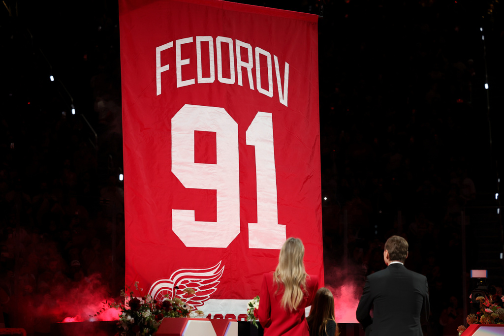 CORRECTS TO SERGEI FEDOROV NOT SERGEI FEDEROV - Former Detroit Red Wings player Sergei Fedorov, right, stands with his wife Karina, left, and children Alexandra and Viktor during his jersey retirement ceremony before an NHL hockey game against the Carolina Hurricanes, Monday, Jan. 12, 2026, in Detroit. (AP Photo/Ryan Sun)