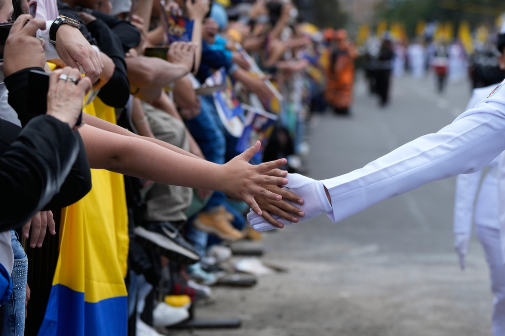 A navy cadet touches hands with spectators watching the Independence Day military parade in Bogotá, Colombia, Monday, July 20, 2026. (AP Photo/Fernando Vergara)