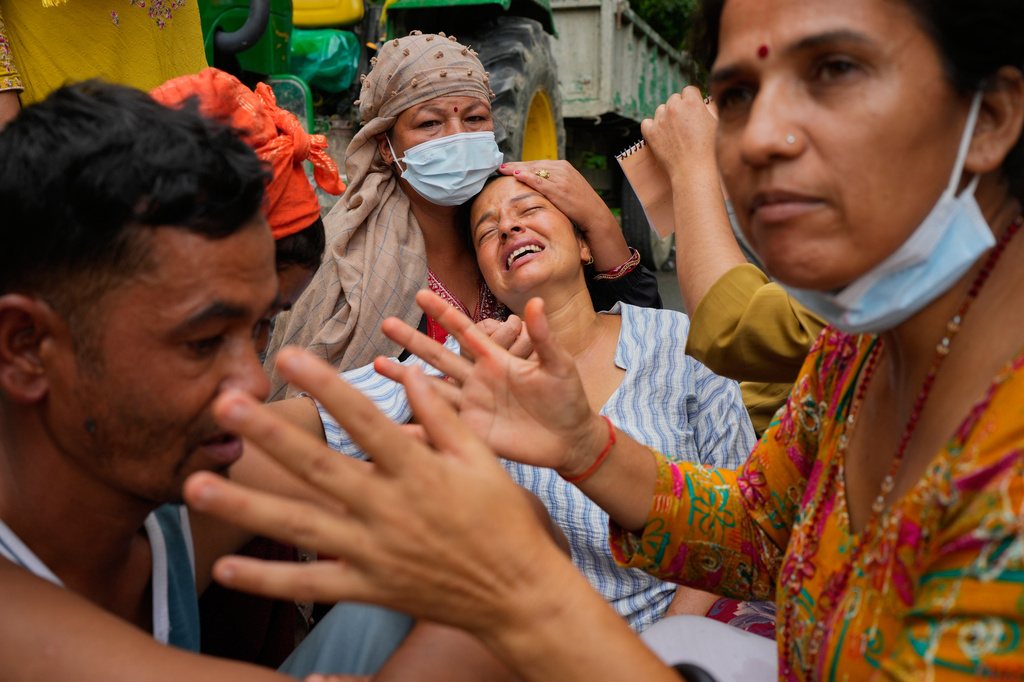 Relatives console Muna Khadka, center, who lost her son Aayush Khada in flash floods, at a cremation ground in Chitwan, Nepal, Monday, Aug. 31, 2026. (AP Photo/Dar Yasin) CORRECTION: Corrects to clarify that this was at a separate cremation ground and not during a mass burial.