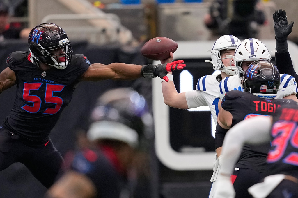 Indianapolis Colts quarterback Riley Leonard, right, is pressured by Houston Texans defensive end Danielle Hunter (55) as he tries to throw during the first half of an NFL football game in Houston, Sunday, Jan. 4, 2026. (AP Photo/David J. Phillip)