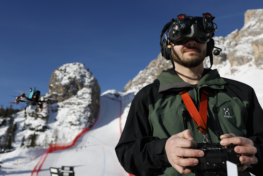 Drone pilot Martin Bochatay controls a drone, left, in front of the Olympia delle Tofane course, ahead of an alpine ski, women's World Cup downhill race, in Cortina d'Ampezzo, Italy, Friday, Jan. 26, 2024. (AP Photo/Alessandro Trovati)
