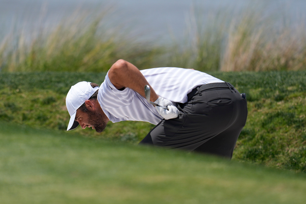 Scottie Scheffler inspects his ball in a bunker on the 18th hole during the second round at the RBC Heritage golf tournament Friday, April 17, 2026, in Hilton Head, S.C. (AP Photo/Mike Stewart)