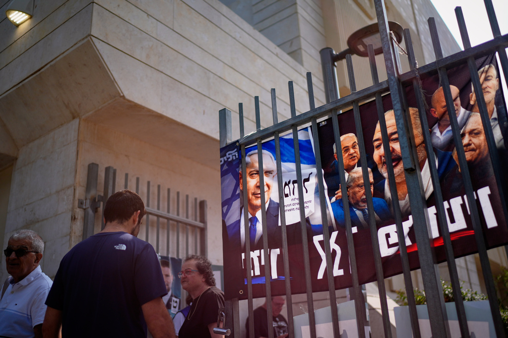 People gather outside a polling station beside campaign posters, including one depicting Benjamin Netanyahu, during Israel's general election in Tel Aviv, Israel, Tuesday, Oct. 27, 2026. (AP Photo/David Goldman)