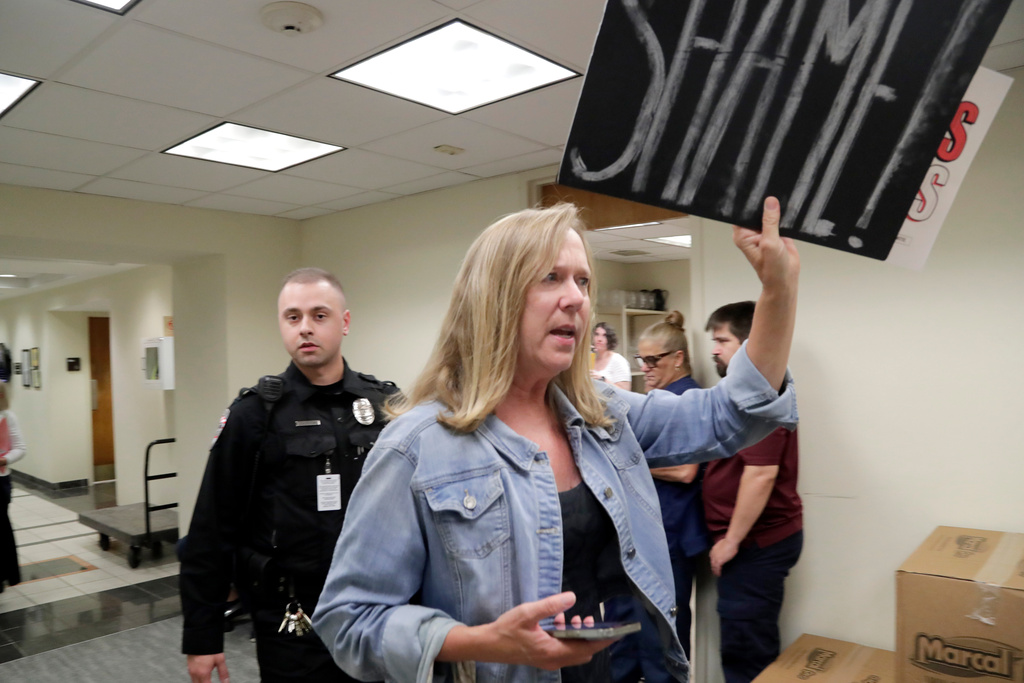 A protester opposed to the proposed redistricting map is escort out by law enforcement during a House Redistricting Committee meeting Tuesday, Oct. 21, 2025, in Raleigh, N.C. (AP Photo/Chris Seward)