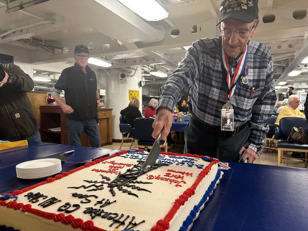 John "Johnny Q" Quinesso Sr, a WWII veteran, cuts a cake during his 100th birthday celebration on Thursday, Feb. 5, 2026 in Camden, N.J., aboard the Battleship New Jersey. (AP Photo/Tassanee Vejpongsa)