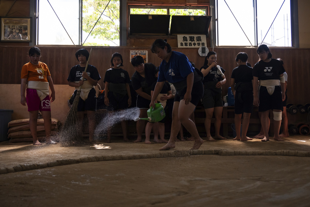 A wrestler sprays water on the clay ring during a practice session at a sumo camp in Tottori Johoku High School in Tottori, Japan, on July 29, 2025. (AP Photo/Louise Delmotte)