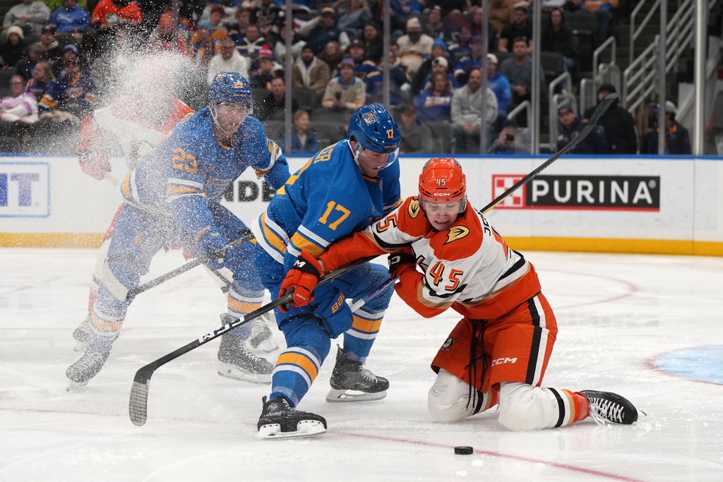 Anaheim Ducks' Beckett Sennecke (45) tries to get his stick on the puck as St. Louis Blues' Cam Fowler (17) and Logan Mailloux (23) defend during the third period of an NHL hockey game Monday, Dec. 1, 2025, in St. Louis. (AP Photo/Jeff Roberson)