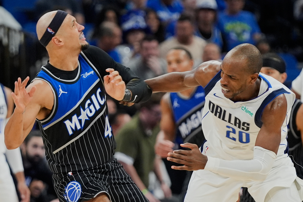 Dallas Mavericks forward Khris Middleton (20) is called for a loose ball foul as he grabs on to Orlando Magic guard Jalen Suggs (4) during the second half of an NBA basketball game, Thursday, March 5, 2026, in Orlando, Fla. (AP Photo/John Raoux)