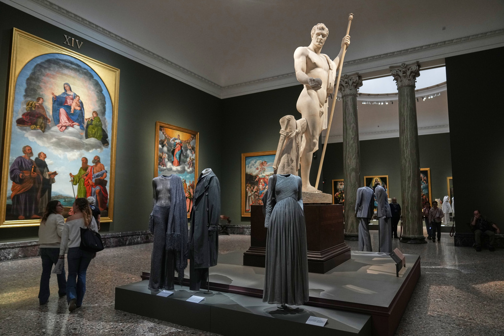 A plaster model of a portrait statue of Napoleon I by Antonio Canova (1803-1806) looms over Giorgio Armani's creations on display during the exhibition “Giorgio Armani – 50 Years” at the Pinacoteca di Brera in Milan, Italy, Wednesday, Sept. 24, 2025. (AP Photo/Antonio Calanni)