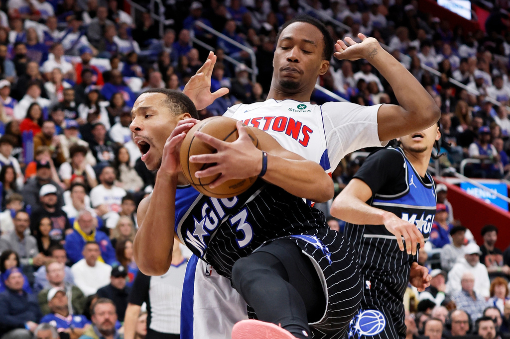Orlando Magic guard Desmond Bane (3) grabs a rebound in front of Detroit Pistons forward Ronald Holland II, top right, during the first half in Game 1 of a first-round NBA basketball playoffs series Sunday, April 19, 2026, in Detroit. (AP Photo/Duane Burleson)