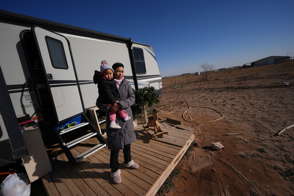 Mayflower Church member Chen Jingjing holds her daughter, Mo Nika, as she surveys the landscape from the porch of the family's trailer in Midland, Texas, Jan. 20, 2025. (AP Photo/Rebecca Blackwell)