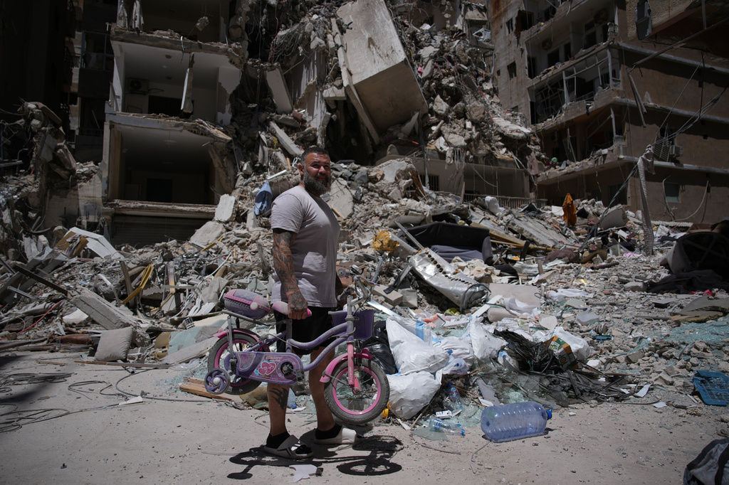 Barber Wissam Srour, 41, holds his daughter's bicycle recovered from his barbershop as he searches for belongings in the rubble of the shop, damaged in an Israeli strike, in the southern port city of Tyre, Lebanon, Friday, June 19, 2026. (AP Photo/Hassan Ammar)