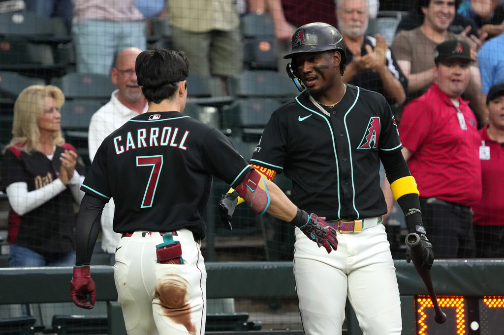 Arizona Diamondbacks' Corbin Carroll (7) celebrates with Geraldo Perdomo, right, after hitting a triple and scoring on an error in the first inning of a baseball game against the San Francisco Giants, Tuesday, May 19, 2026, in Phoenix. (AP Photo/Rick Scuteri) CORRECTION: Corrects to May 19 not May 20.