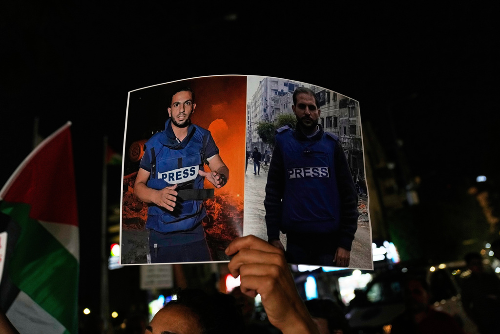 A woman carries a poster showing Palestinian journalists Anas al-Sharif, left, and Mohamed Qreiqeh that Israel's military targeted and killed with an airstrike late Sunday in Gaza, during a protest in the West Bank city of Ramallah Monday, Aug. 11, 2025. (AP Photo/Nasser Nasser)