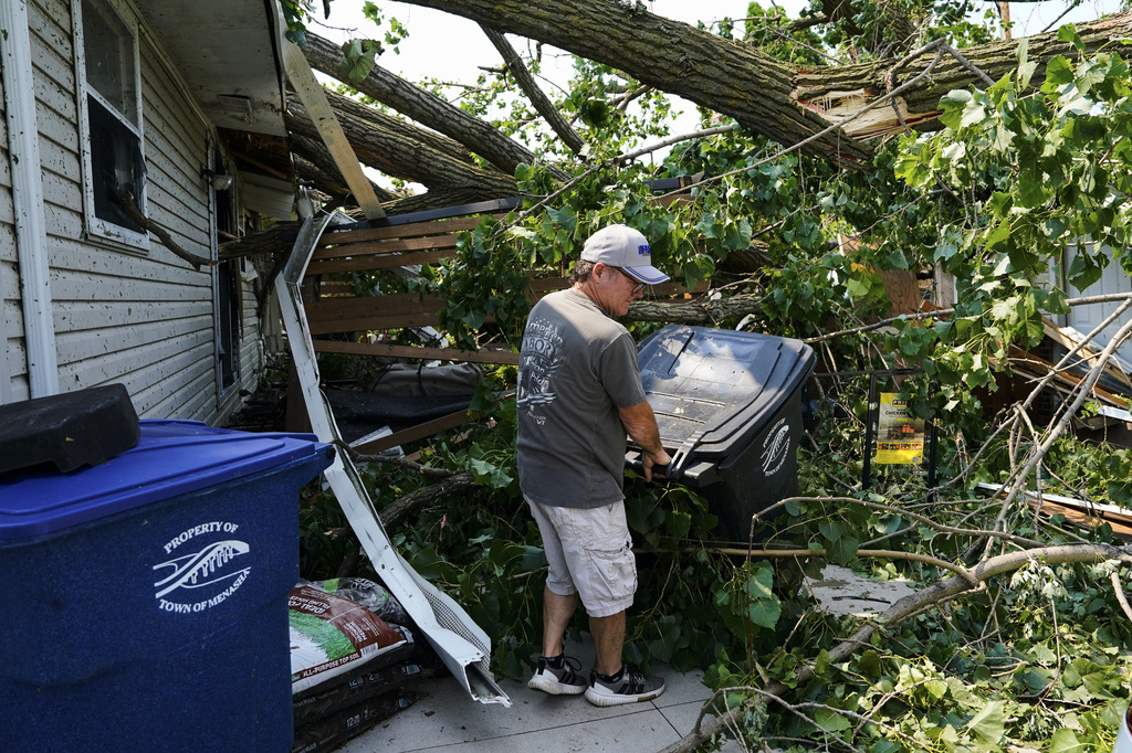 A man helps clear debris from the backyard of a damaged house after a tornado hit the day before, Tuesday, July 28, 2026, in Appleton, Wis. (AP Photo/Kayla Wolf)