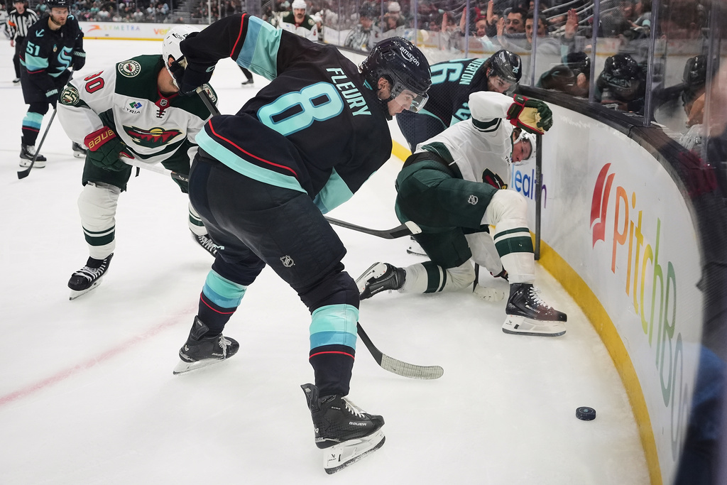 Seattle Kraken defenseman Cale Fleury (8) tries to clear the puck agasint Minnesota Wild left wing Matt Boldy, right, during the second period of an NHL hockey game Thursday, Jan. 8, 2026, in Seattle. (AP Photo/Lindsey Wasson)