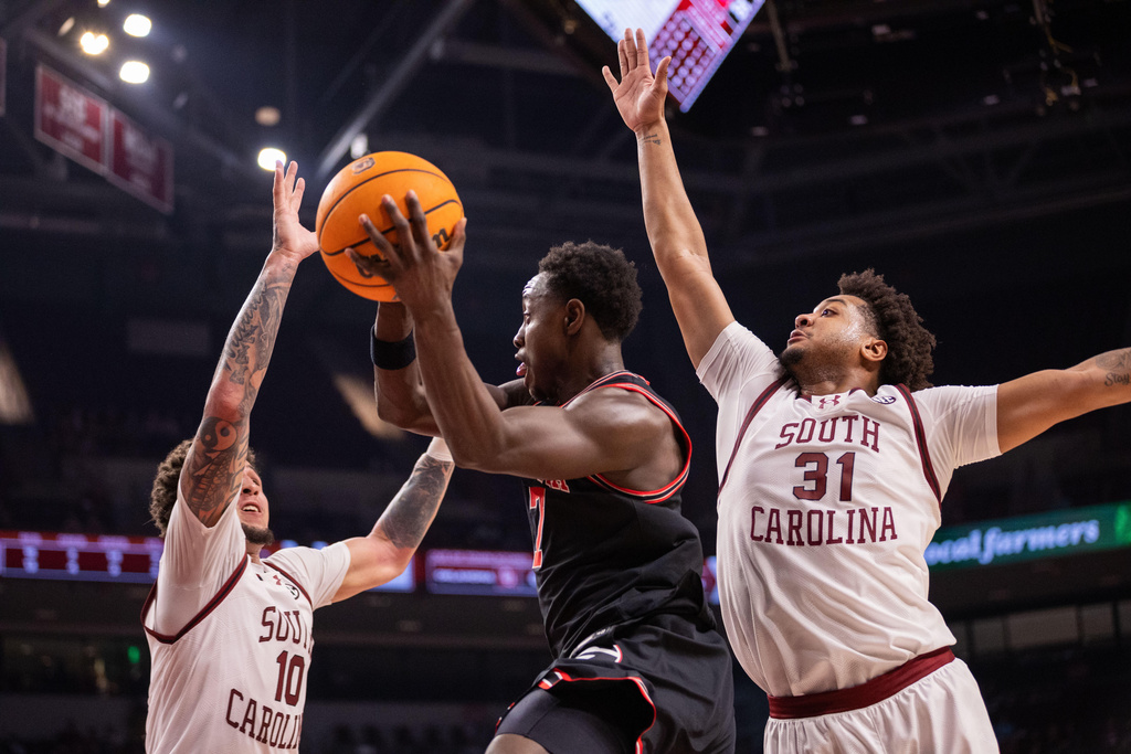 Georgia guard Justin Bailey (7) passes away the ball against South Carolina forward Myles Stute (10) and forward Elijah Strong (31) during the first half of an NCAA college basketball game Saturday, Jan. 10, 2026, in Columbia, S.C. (AP Photo/Scott Kinser)