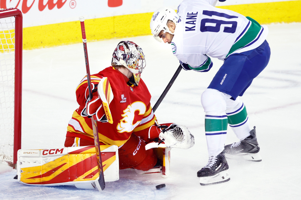 Vancouver Canucks' Evander Kane (91) has his shot stopped by Calgary Flames goalie Dustin Wolf during second-period NHL hockey game action in Calgary, Alberta, Saturday, March 28, 2026. (Larry MacDougal/The Canadian Press via AP)