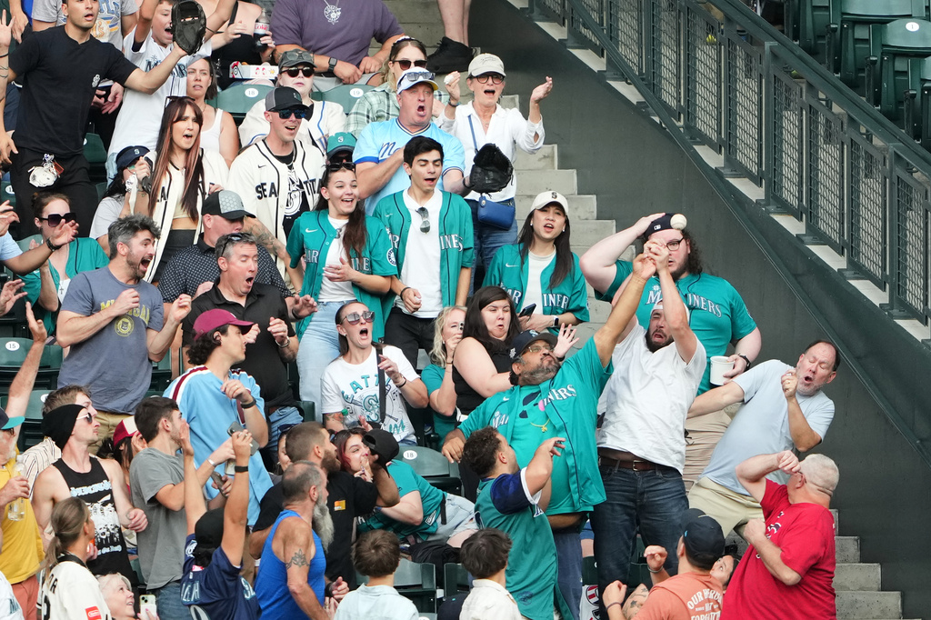 Fans vie for the solo home run hit by Seattle Mariners' Cal Raleigh during the second inning of a baseball game against the Philadelphia Phillies, Tuesday, Aug. 25, 2026, in Seattle. (AP Photo/Lindsey Wasson)