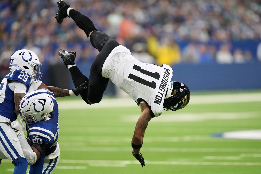 Jacksonville Jaguars wide receiver Parker Washington (11) catches a pass as Indianapolis Colts cornerback Mekhi Blackmon (29) and safety Nick Cross (20) defend during the first half of an NFL football game Sunday, Dec. 28, 2025, in Indianapolis. (AP Photo/AJ Mast)