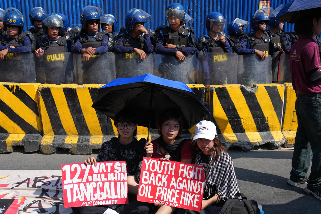 FILE - Protesters hold slogans beside police during a rally by transport workers and activists protesting the rise in oil prices on March 27, 2026, near the Malacanang presidential palace in Manila, Philippines. (AP Photo/Aaron Favila, File)