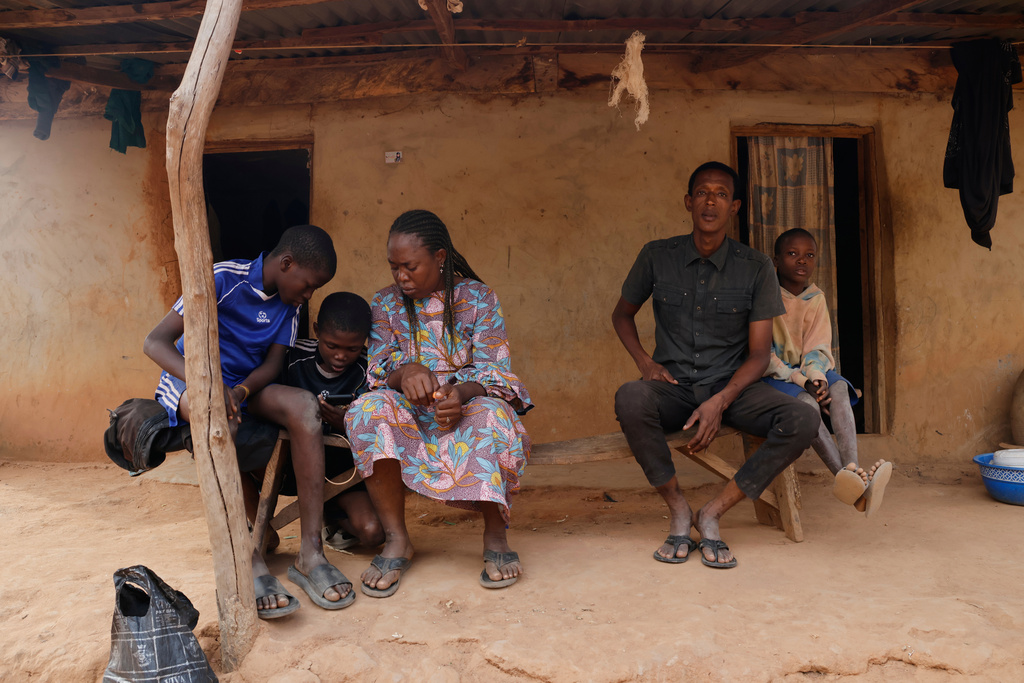 Precious Njikonye, centre, the mother of a student at St. Mary's Catholic School, who was abducted by gunmen and later released, sits outside her house in Papiri, Nigeria, Wednesday, Dec. 10, 2025. (AP Photo/Afolabi Sotunde)
