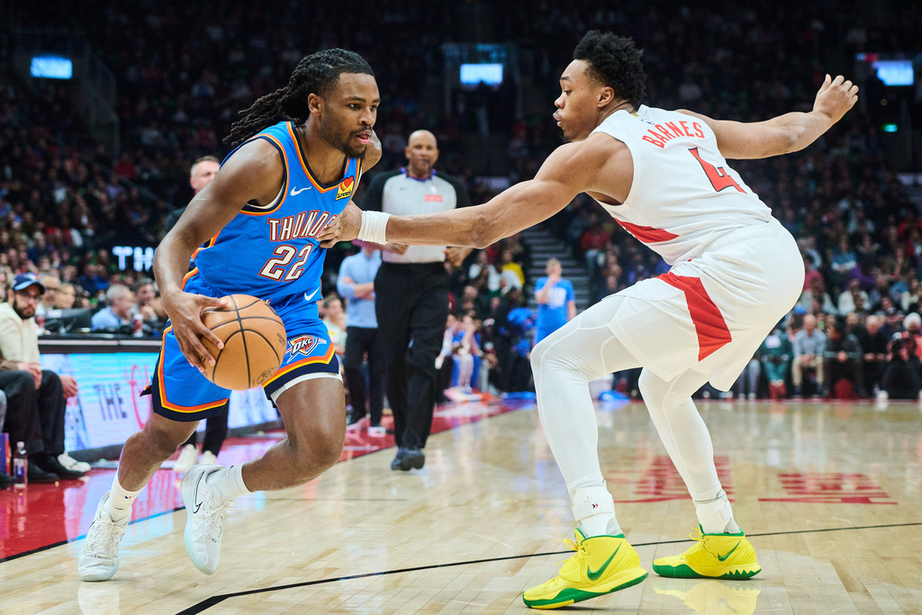Oklahoma City Thunder's Cason Wallace (22) drives past Toronto Raptors' Scottie Barnes (4) during the first half of an NBA basketball game in Toronto, on Tuesday, Feb. 24, 2026. (Sammy Kogan/The Canadian Press via AP)