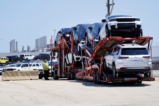 FILE - A transport carrying new cars arrives at a Stellantis facility July 10, 2023, in Belvidere. Ill. (AP Photo/Charles Rex Arbogast, File) FILE - A transport carrying new cars arrives at a Stellantis facility July 10, 2023, in Belvidere. Ill. (AP Photo/Charles Rex Arbogast, File)