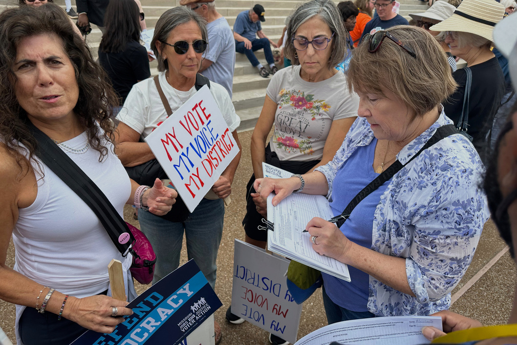 Lauren Bakker, of Webster Groves, Mo., signs a petition for a proposed constitutional amendment limiting the Legislature's ability to revise voter-approved, citizen-initiated ballot measures, as others gather for a rally at the state Capitol in Jefferson City, Mo., on Wednesday, Sept. 10, 2025. (AP Photos/David A. Lieb)