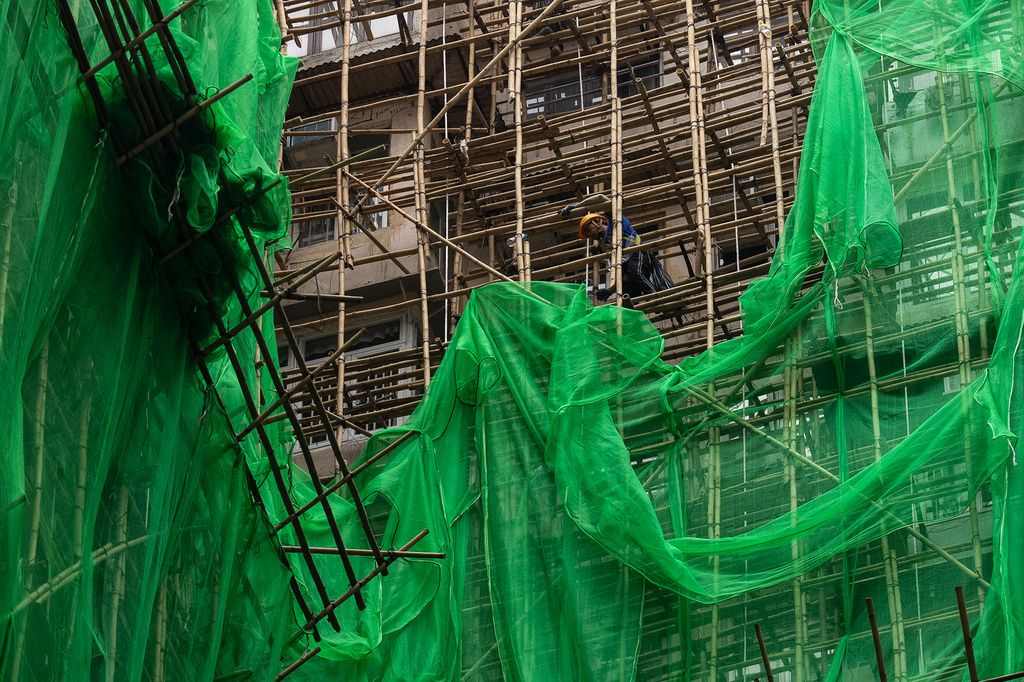 Construction workers remove scaffolding nets from a renovation project in Quarry Bay district after the deadly fire at Wang Fuk Court, in the Tai Po district of Hong Kong's New Territories, Thursday, Dec 4, 2025. (AP Photo/Chan Long Hei)