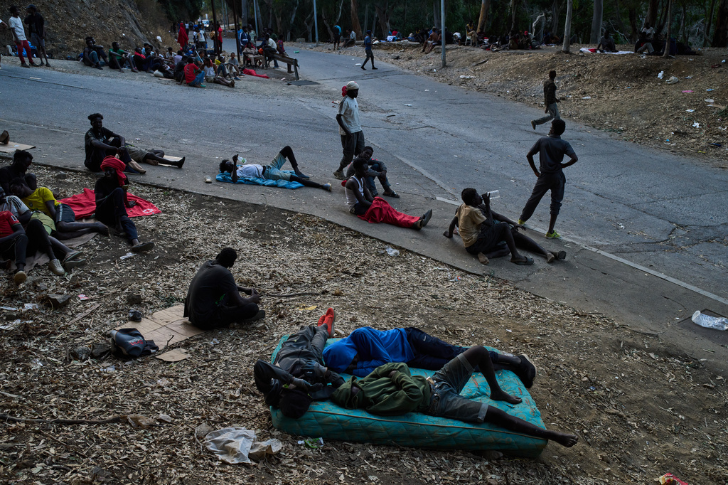 Migrants who crossed into Spain from Morocco sit outside the temporary immigrant stay center (CETI) in the Spanish enclave of Ceuta, Sunday, Aug. 2, 2026. (AP Photo/Bernat Armangue)