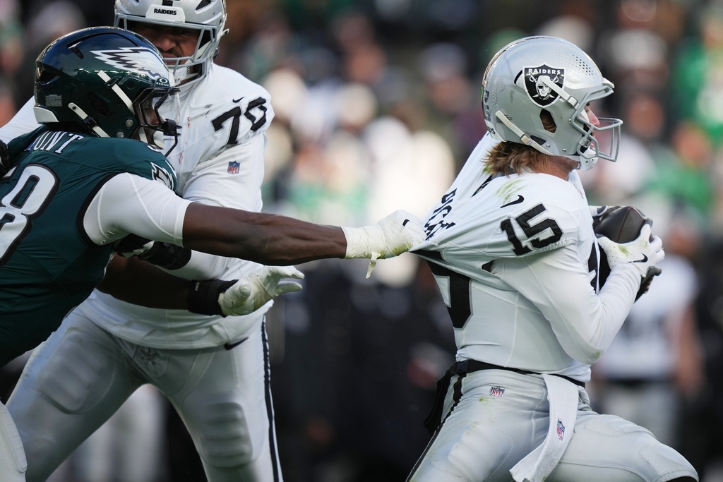 Philadelphia Eagles linebacker Jalyx Hunt (58) grabs Las Vegas Raiders quarterback Kenny Pickett (15) during the second half of an NFL football game Sunday, Dec. 14, 2025, in Philadelphia. (AP Photo/Matt Slocum)