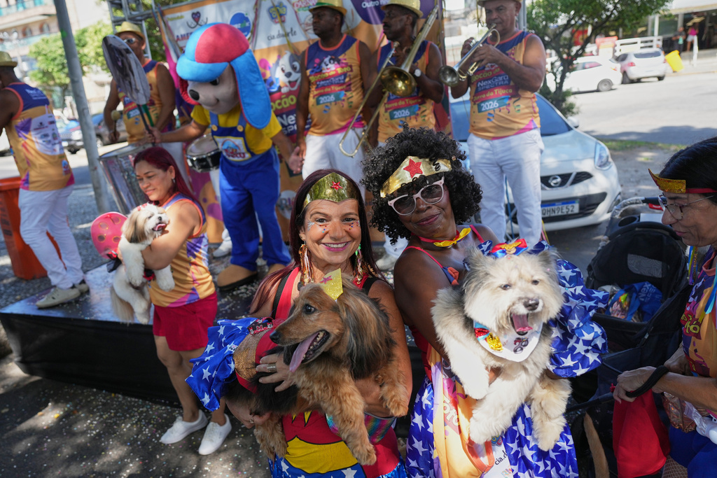 Owners and their pets pose for a photo at the "Blocao" Carnival dog parade in Rio de Janeiro, Saturday, Feb. 14, 2026. (AP Photo/Silvia Izquierdo)