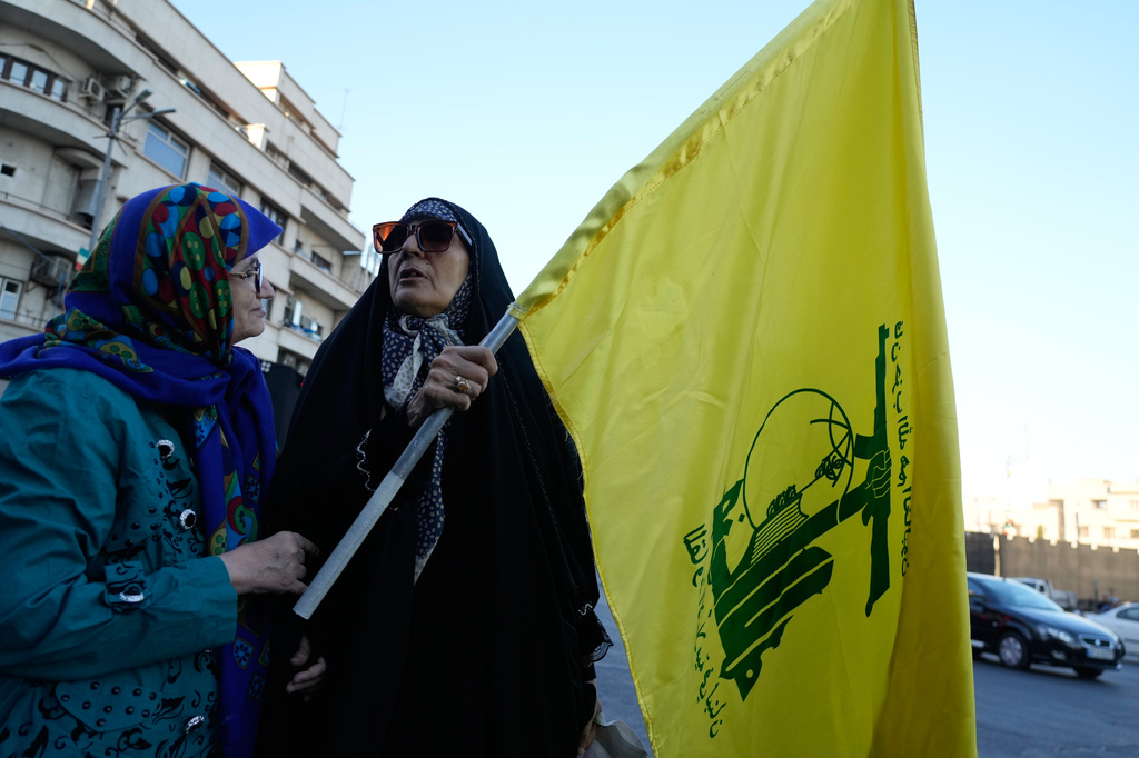 A woman holds a flag of Lebanon's militant Hezbollah group during a small group gathering at the Islamic Revolution square in Tehran, Iran, Sunday, June 14, 2026. (AP Photo/Vahid Salemi)