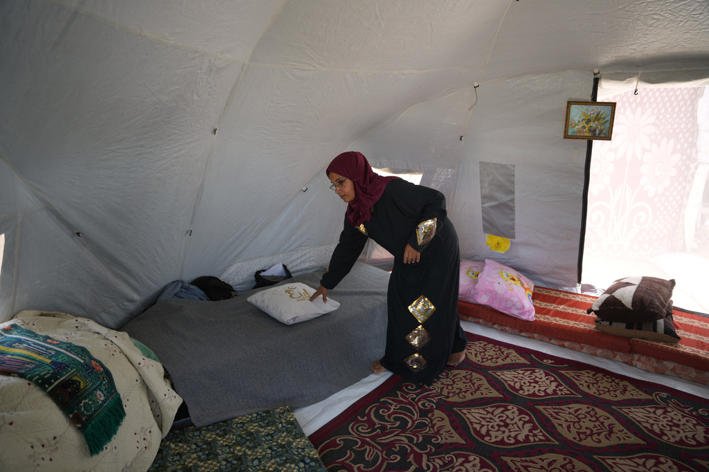 Majida Abu Jarad places a pillow on a bed inside the tent where she lives with her family at a camp for displaced Palestinians in Khan Younis, Wednesday, May 13, 2026. (AP Photo/Abdel Kareem Hana)