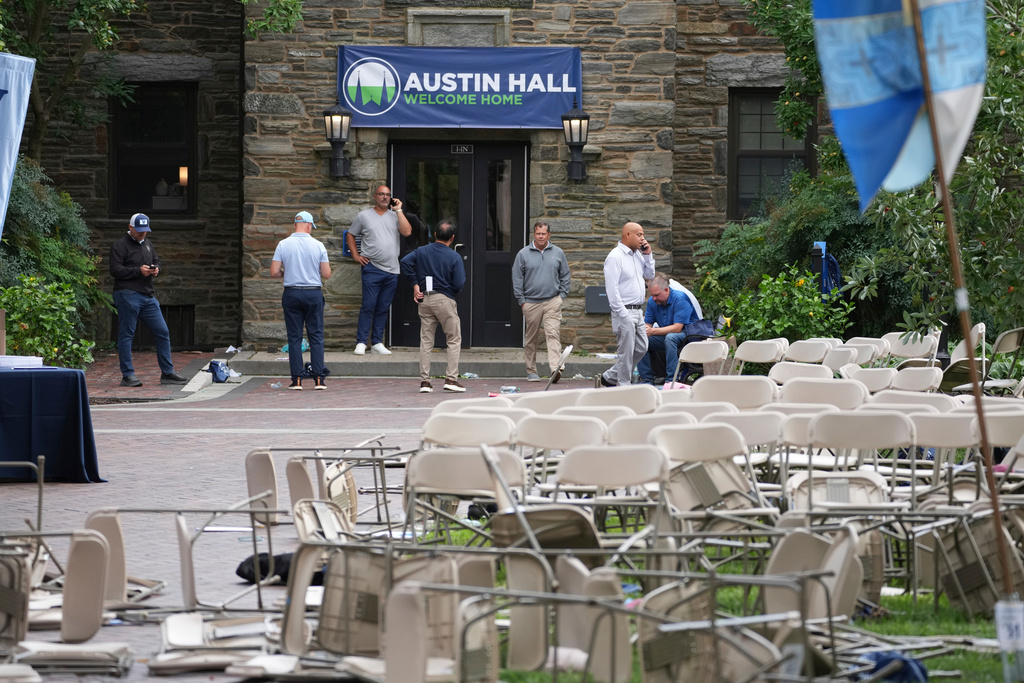 People use there phones in a mess of toppled chairs at the Villanova University campus where an active shooter was reported Thursday, Aug. 21, 2025, in Villanova, Pa. (AP Photo/Matt Slocum)