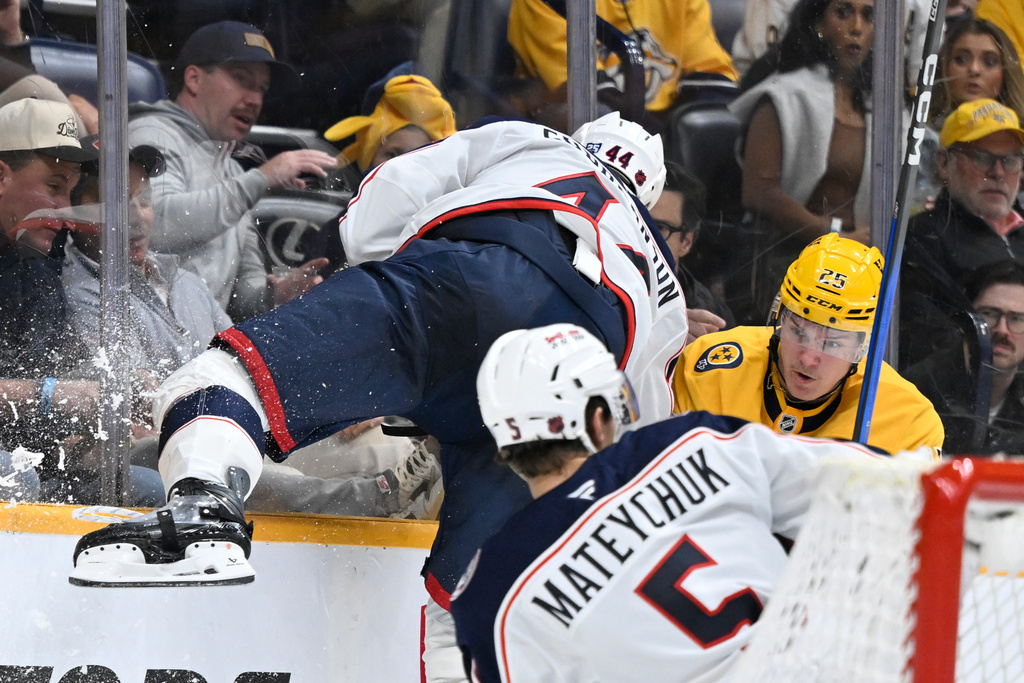 Columbus Blue Jackets defenseman Erik Gudbranson (44) goes high on the glass while trying to check Nashville Predators right wing Joakim Kemell (25) as Blue Jackets defenseman Denton Mateychuk (5) controls the puck during the second period of an NHL hockey game Thursday, Oct. 9, 2025, in Nashville, Tenn. (AP Photo/John Amis)