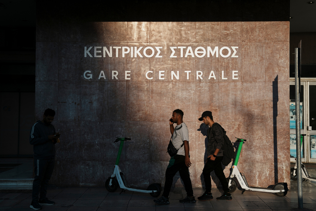 People walk outside the closed main railway station during a nationwide 24-hour strike, as labor demand higher wages and the withdrawal of a bill that changes work hours in Athens, Greece, Wednesday, Oct. 1, 2025. (AP Photo/Thanassis Stavrakis)