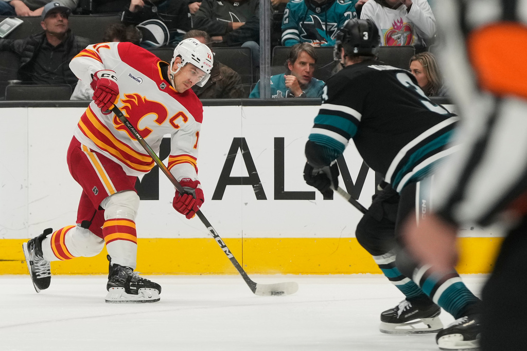 Calgary Flames center Mikael Backlund, left, shoots the puck against San Jose Sharks defenseman John Klingberg during the second period of an NHL hockey game in San Jose, Calif., Tuesday, Dec. 16, 2025. (AP Photo/Jeff Chiu)